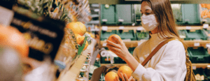 Masked woman picking oranges in supermarket